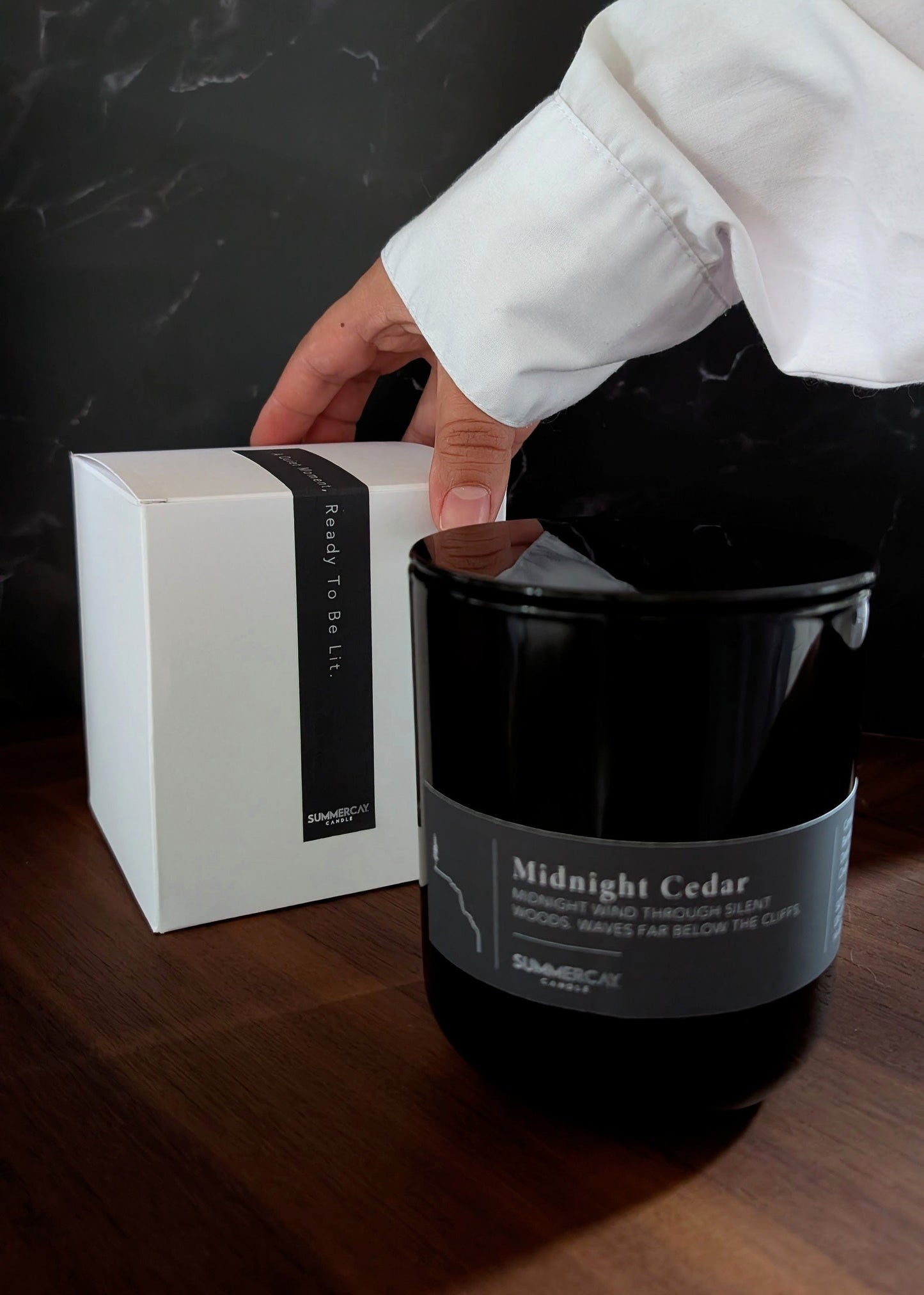 Black candle labeled 'Midnight Cedar' with a white box on a dark surface