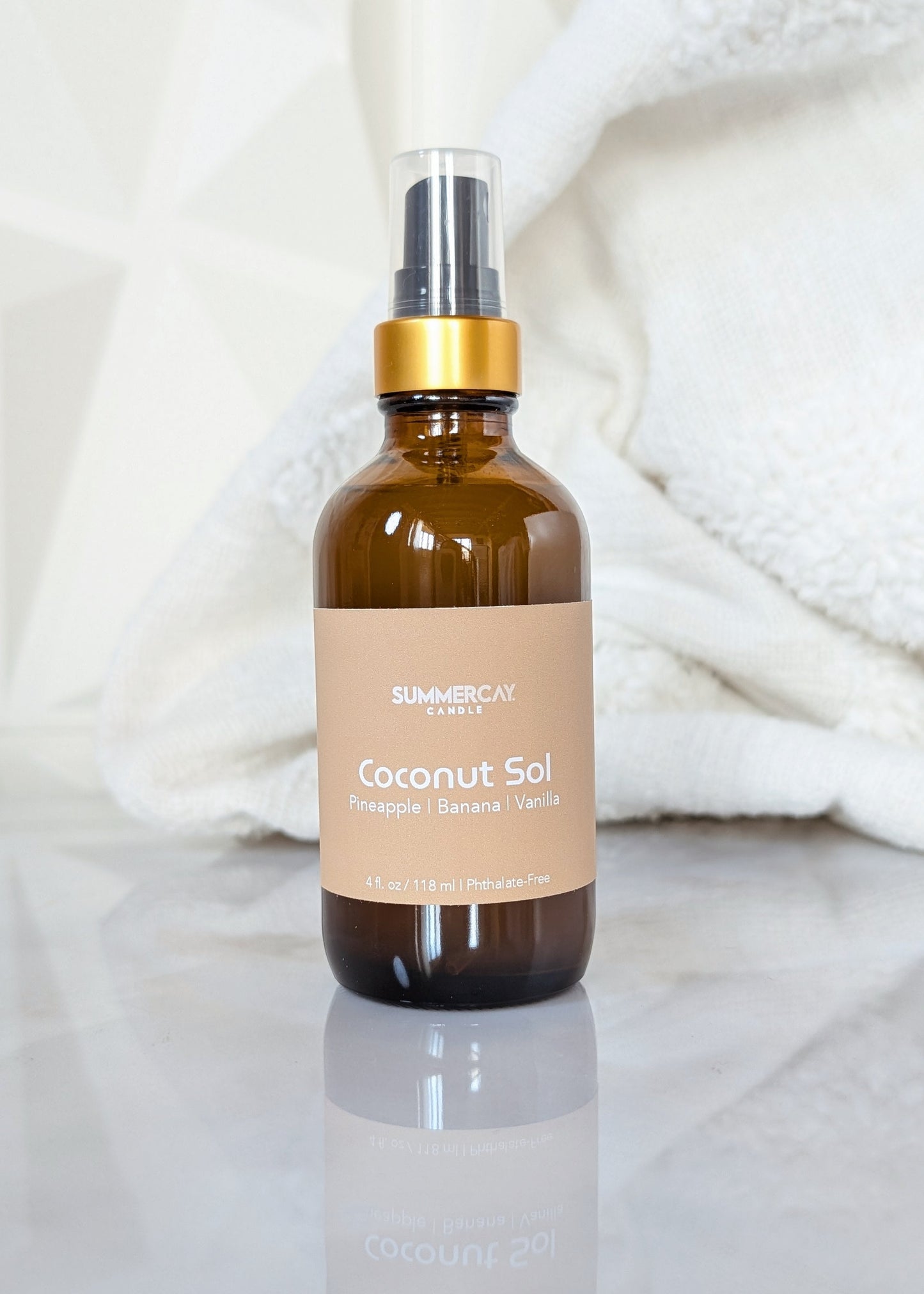 Coconut Sol room and linen spray in an amber glass bottle with black and gold top on a white background