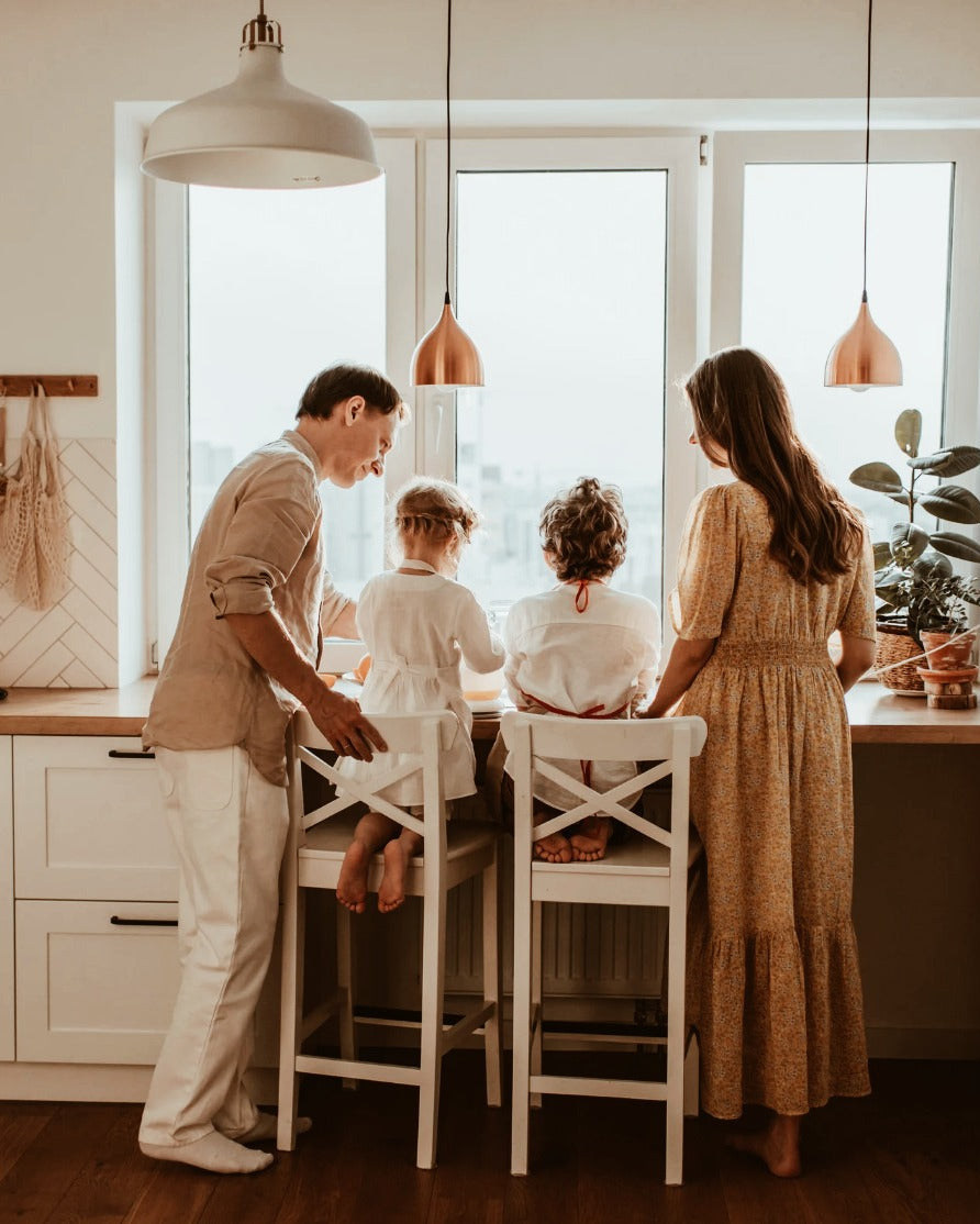 Family of four in a modern kitchen with large windows.