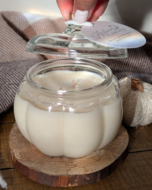 Glass jar with a white candle on a wooden coaster, hand reaching to light it.