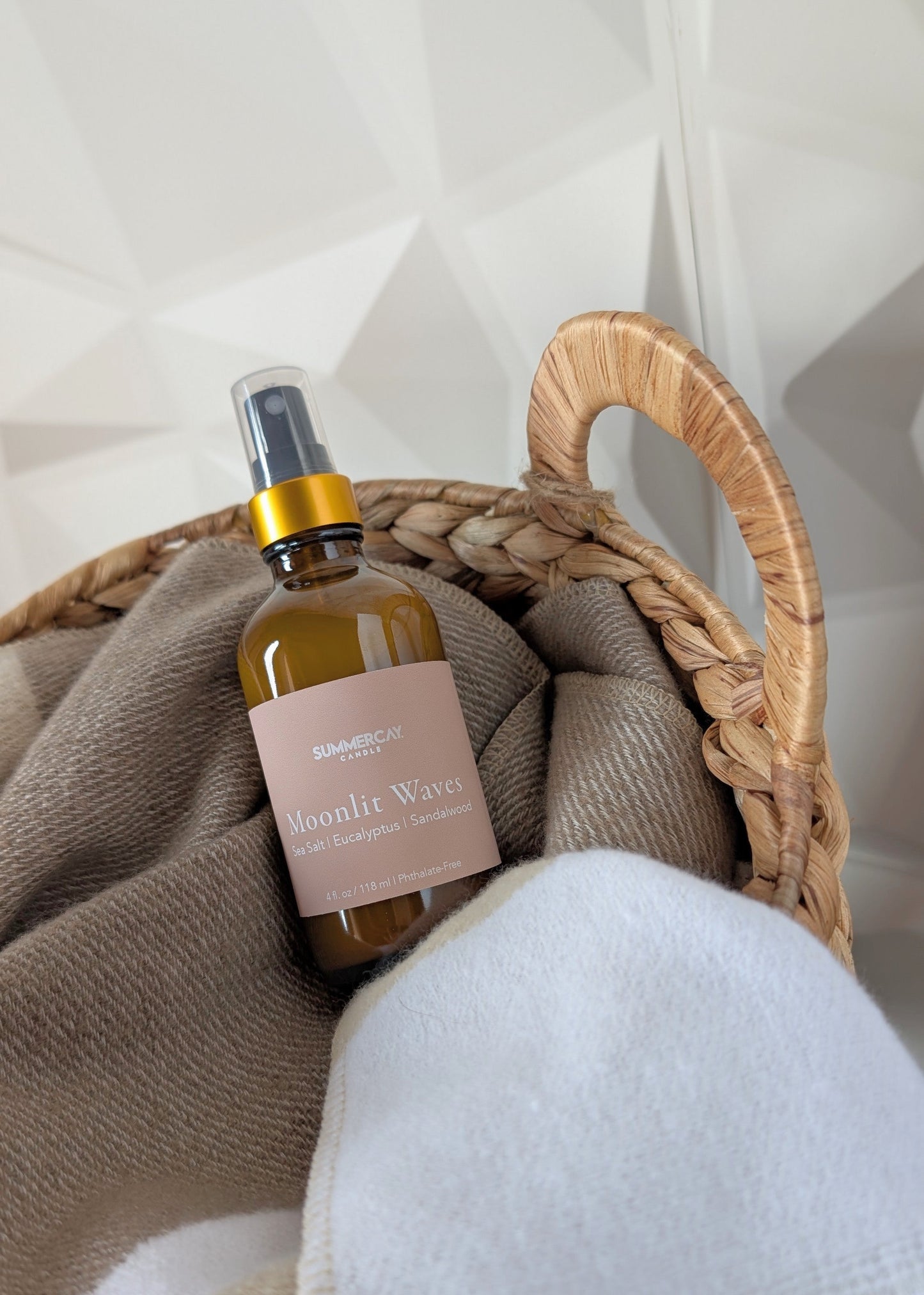 room and linen spray in a basket with a neutral colored blanket and white background
