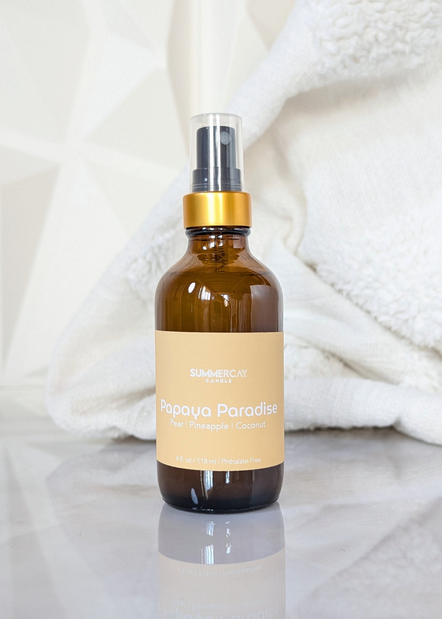 Papaya Paradise scented room spray in an amber glass spray bottle with gold and black top on a white background