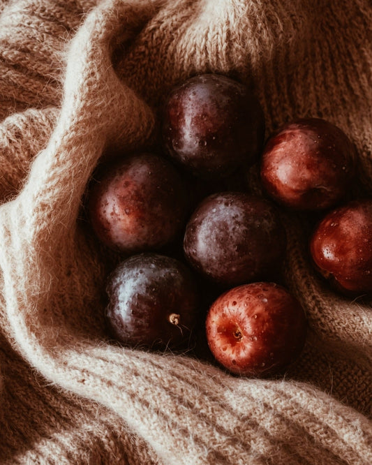 ripe plums sitting on a cashmere sweater