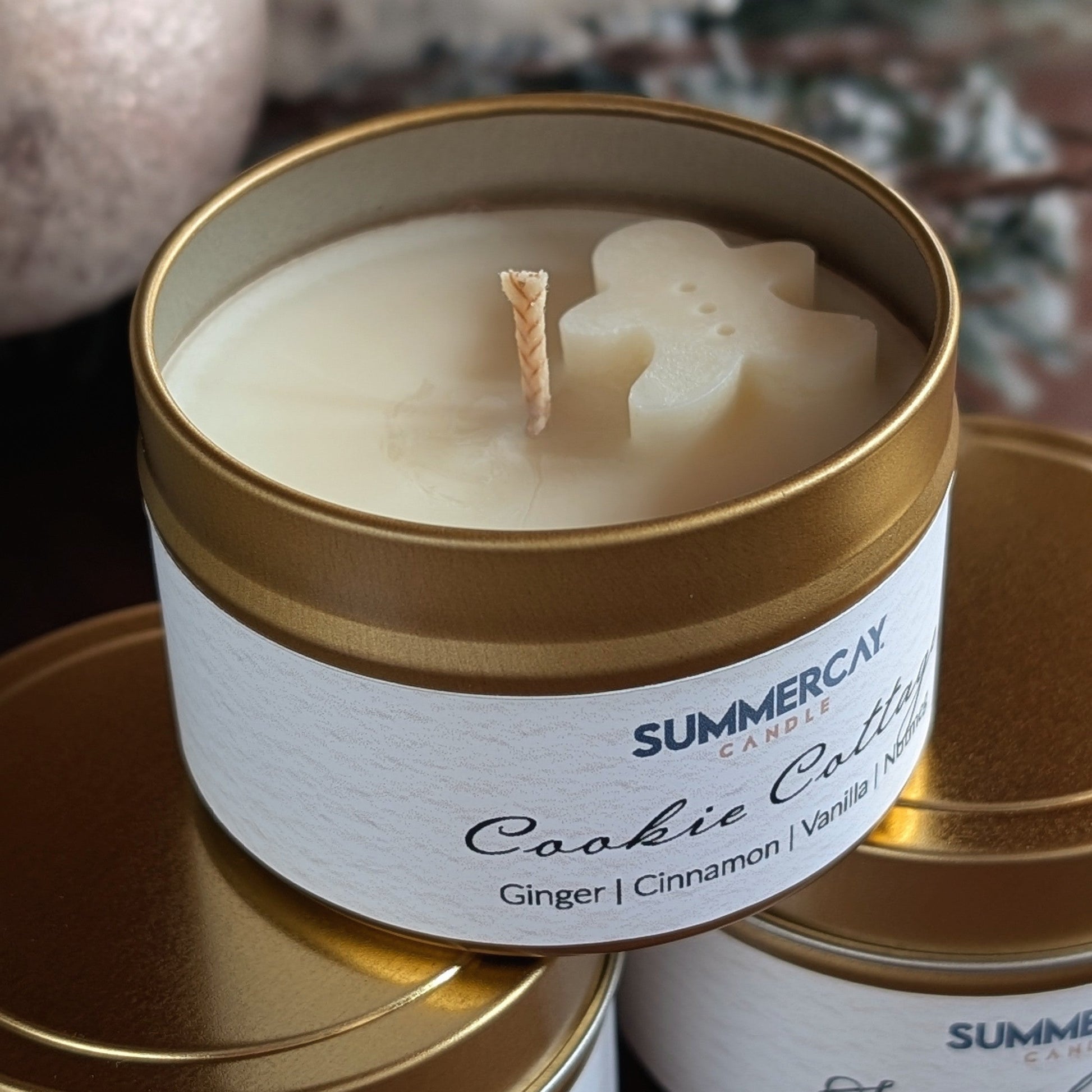 small gold candle tin with a gingerbread wax melt on top on a festive setting.