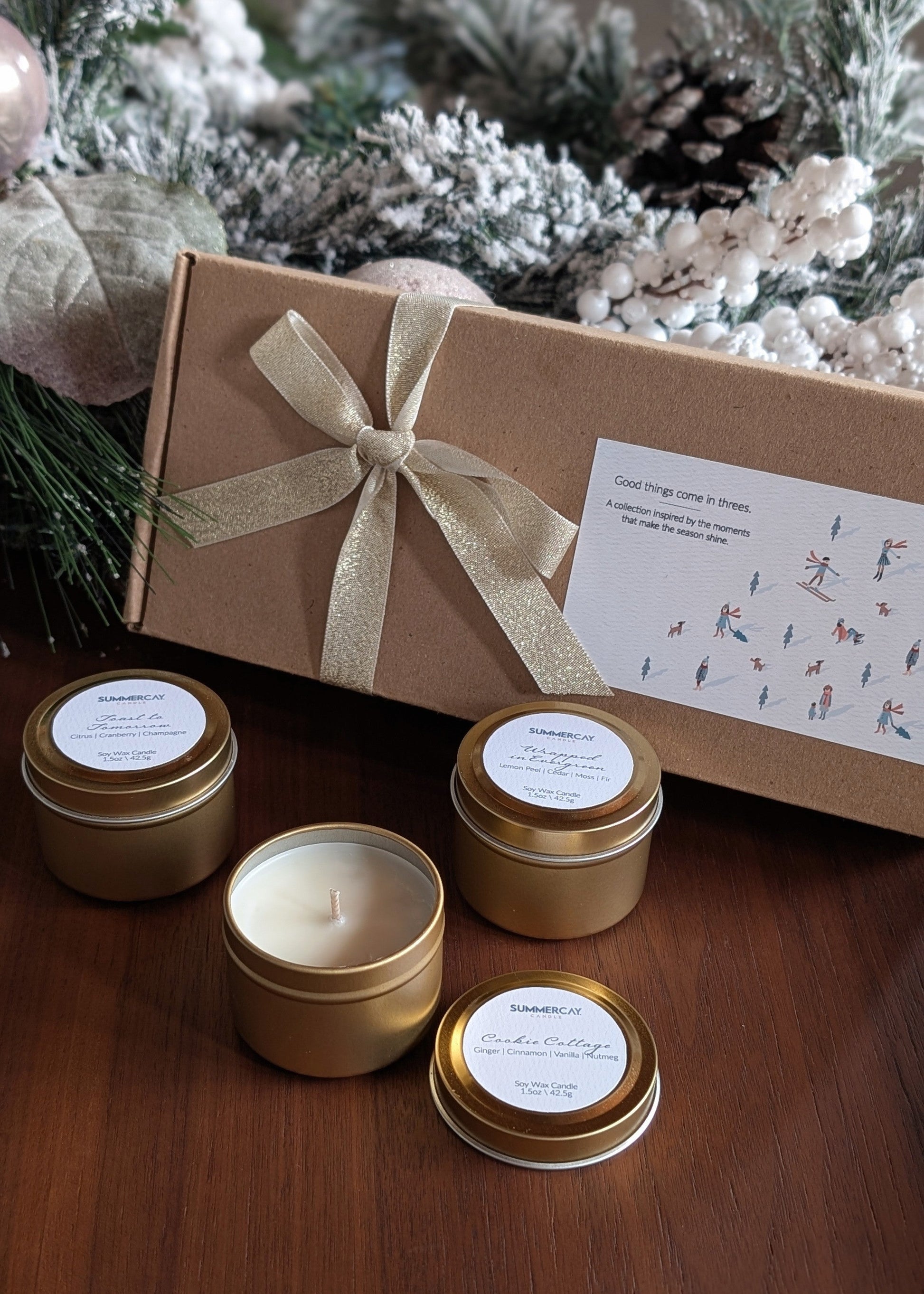 Set of small candles with gold lids and a decorative box on a wooden surface.