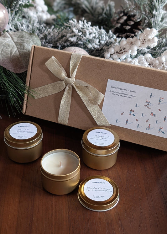 Set of small candles with gold lids and a decorative box on a wooden surface.