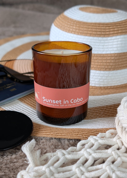 Sunset in Cabo amber glass candle with a beach hat sunglasses and beach woven bag