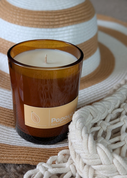 Candle in a brown glass jar with a label on a woven surface