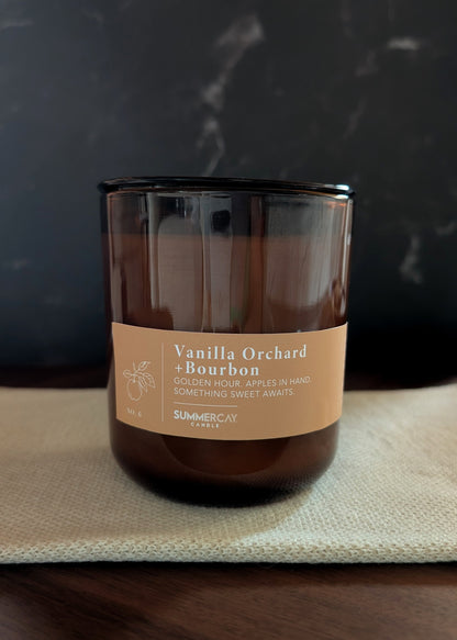 Vanilla Orchard Bourbon candle on a dark surface with a blurred background