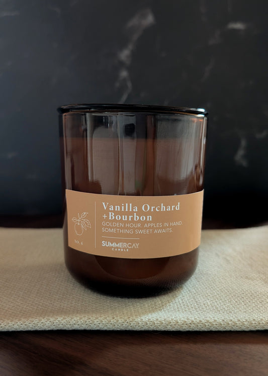 Vanilla Orchard Bourbon candle on a dark surface with a blurred background