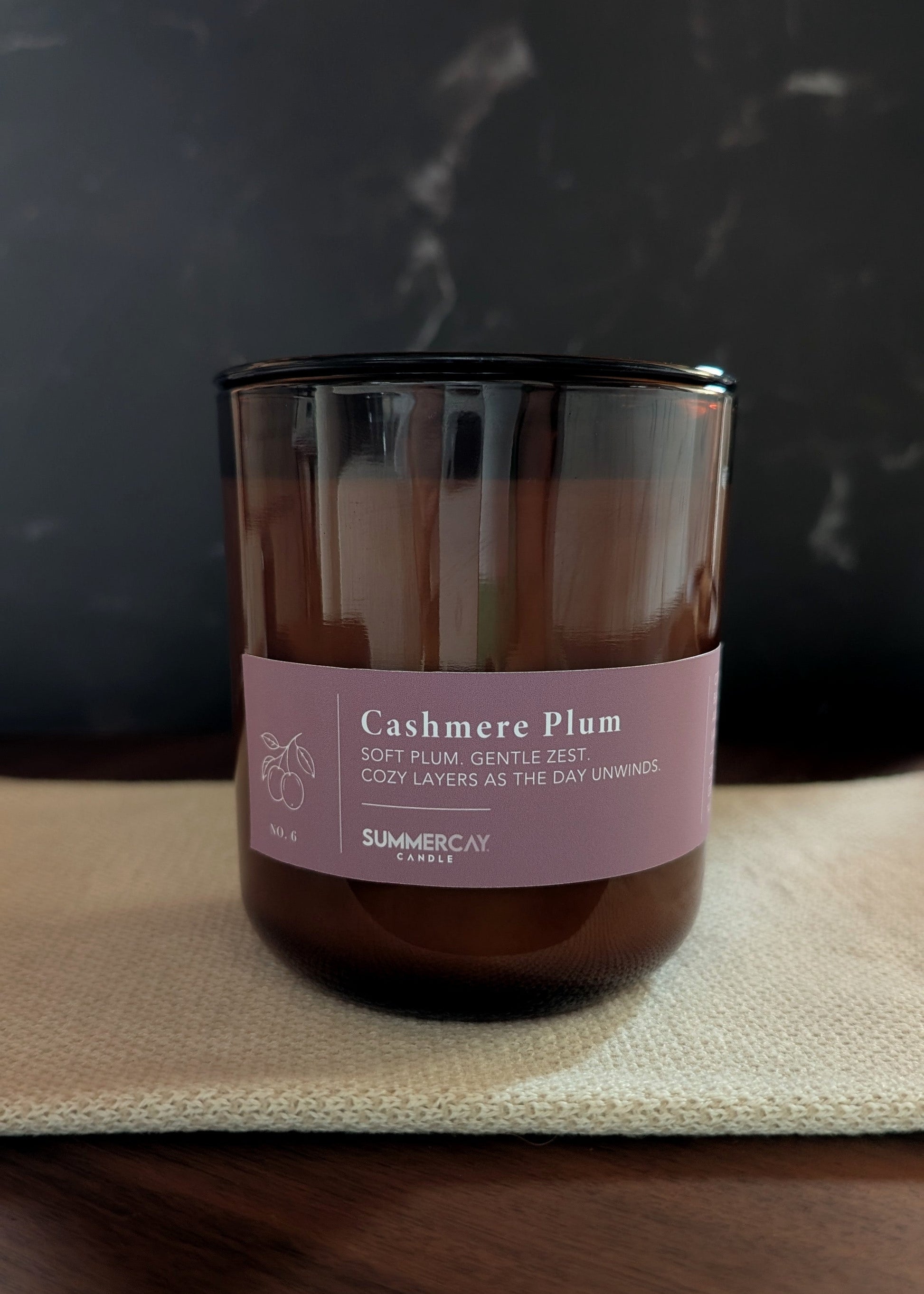 Candle with a muted purple label on a dark background