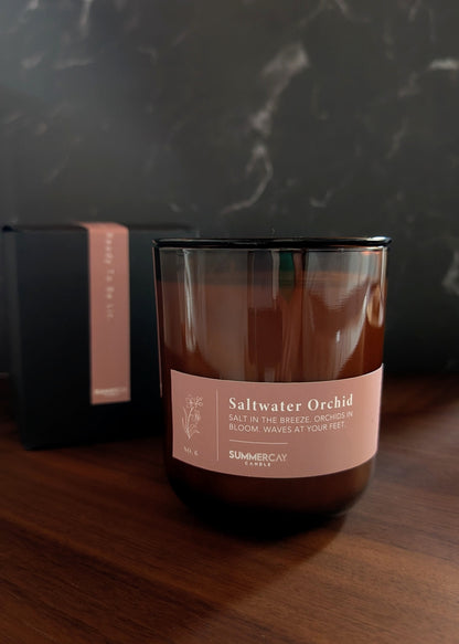Candle with 'Saltwater Orchid' label on a wooden surface