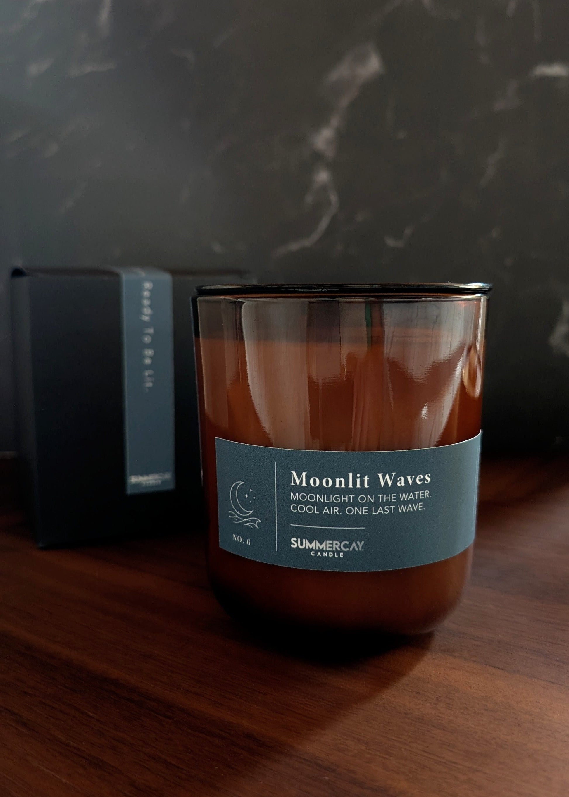 Moonlit Waves amber glass candle with black gift box behind it and a dark background.