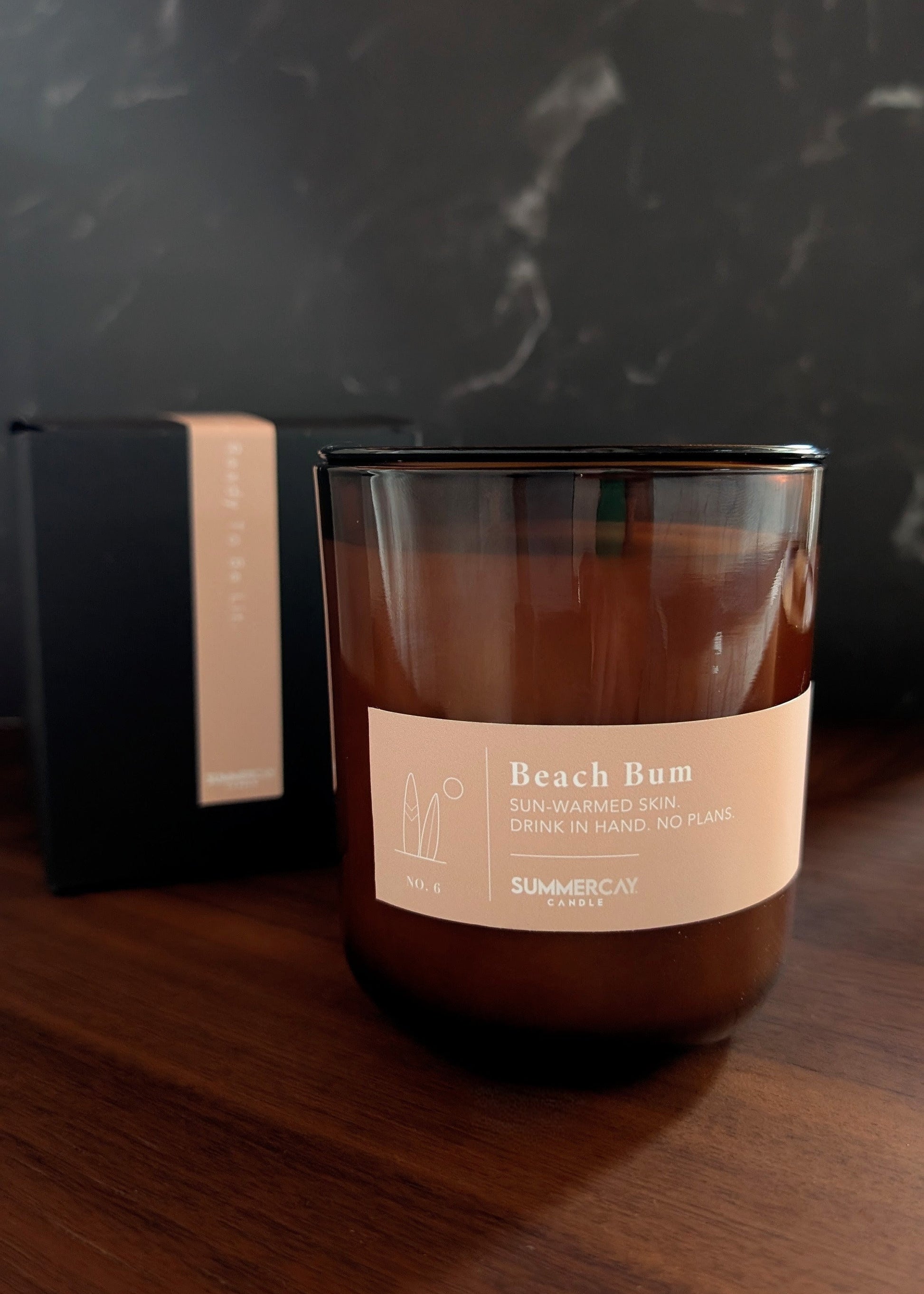 Beach Bum scented candle with gift box behind it and dark background.