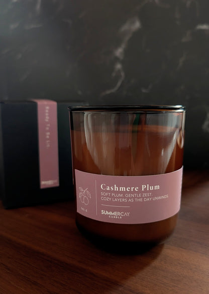 Cashmere Plum candle with gift box behind it with a dark background.