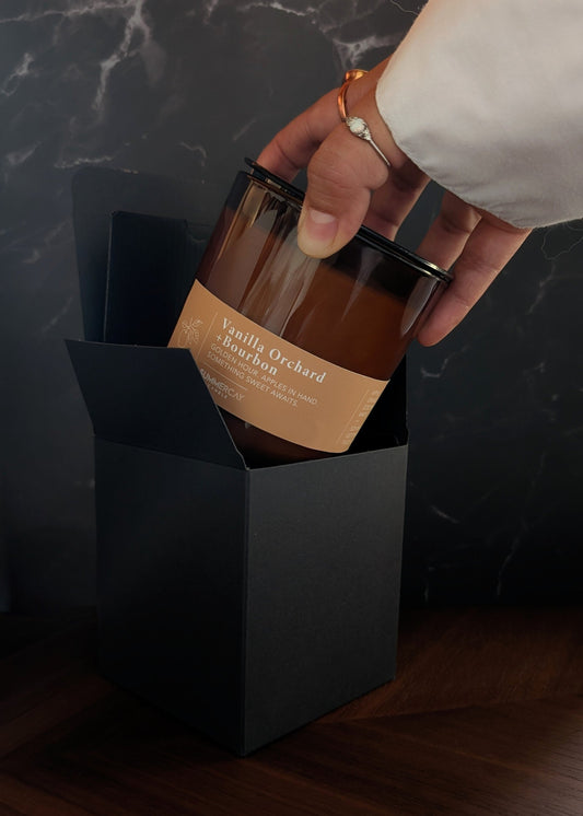 hand pulling out a Vanilla Orchard and bourbon scented candle out of it's gift box.