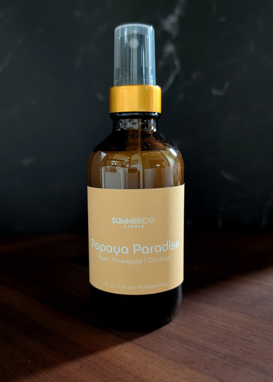Papaya Paradise room spray on wooden table and a dark background.