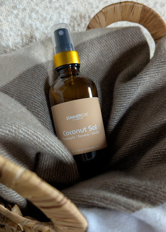 Coconut Sol room spray in a woven basket with a soft blanket.