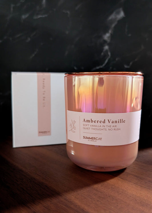 Candle with 'Ambered Vanille' label on a wooden surface with a dark marble background