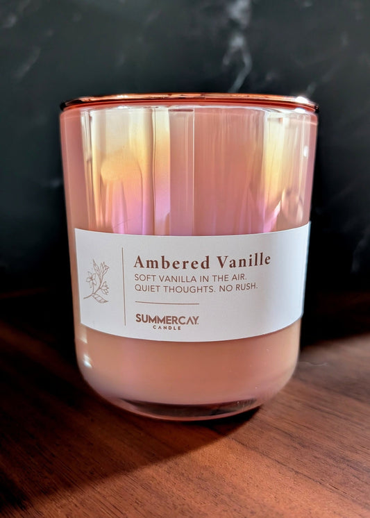 Candle with 'Ambered Vanille' label on a wooden surface