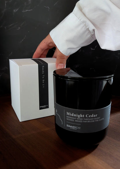 Black candle labeled 'Midnight Cedar' with a white box on a dark surface