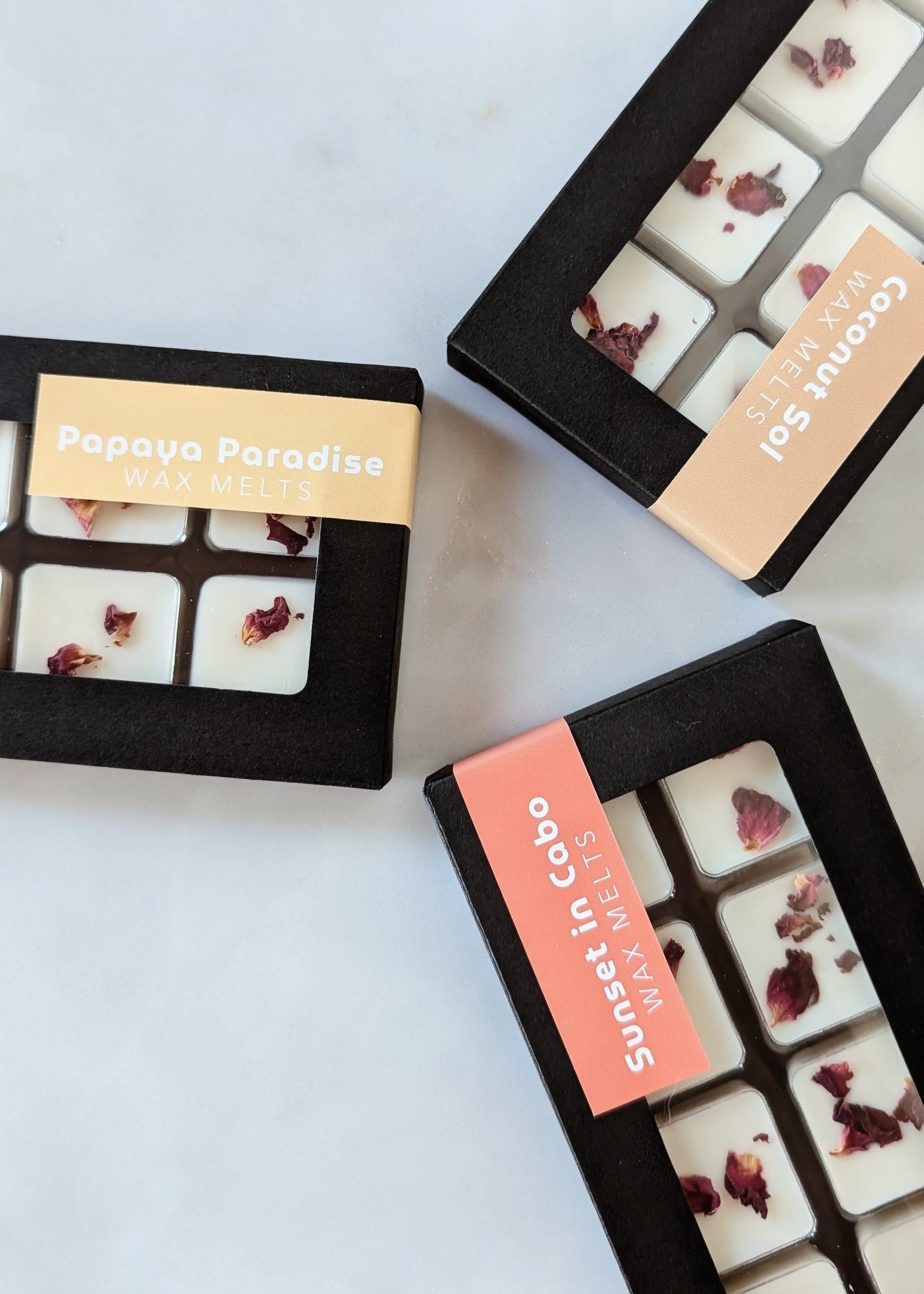 Three boxes of assorted wax melts with visible brand names on a light background