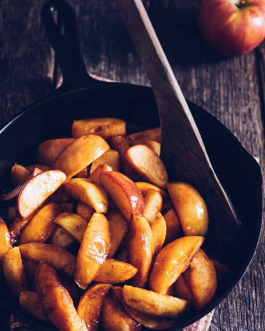 Caramelized apples in a black skillet on a wooden surface