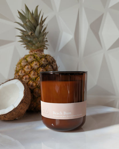 Candle labeled 'Beach Bum' with a pineapple and coconut on a geometric-patterned background