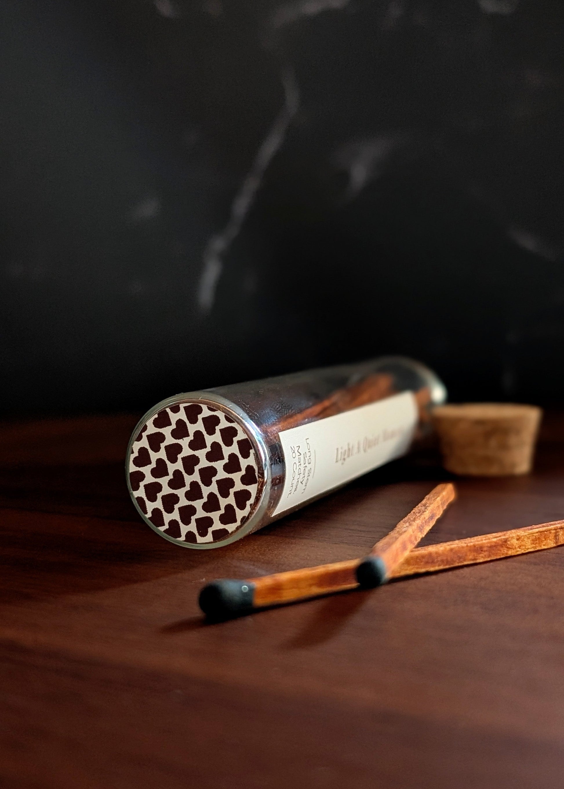 Matches with a decorative cylindrical container on a dark surface