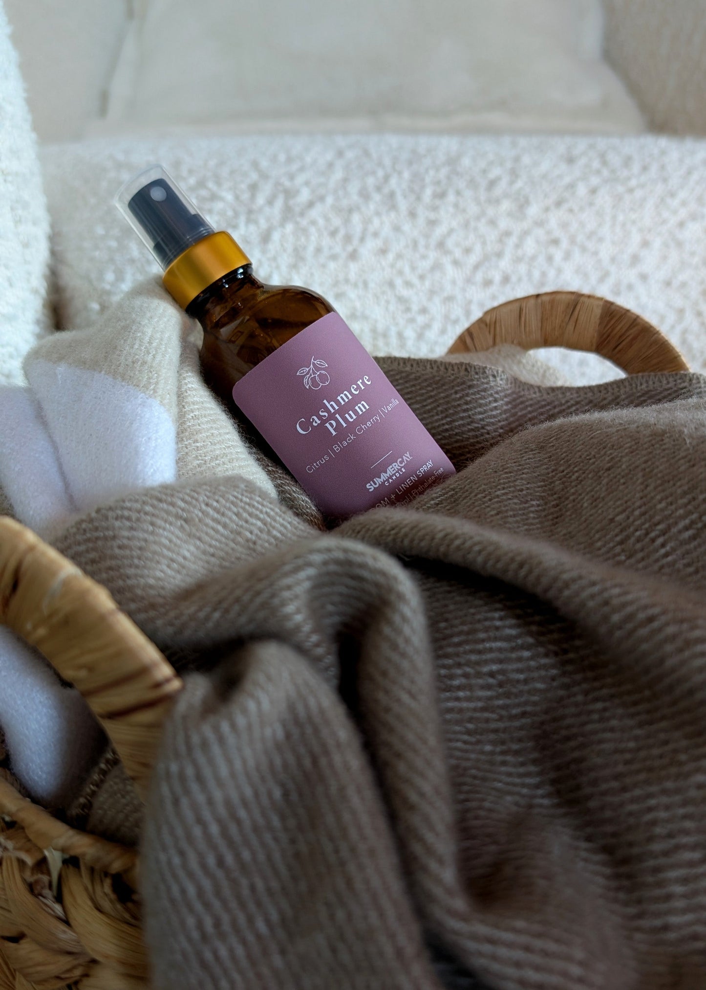 room spray inside a woven basket with a blanket. 