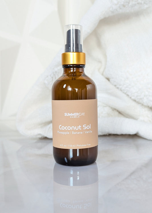 Coconut Sol room and linen spray in an amber glass bottle with black and gold top on a white background