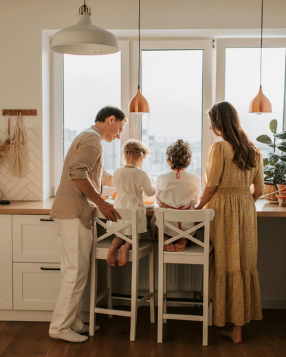 Family of four in a modern kitchen with large windows.