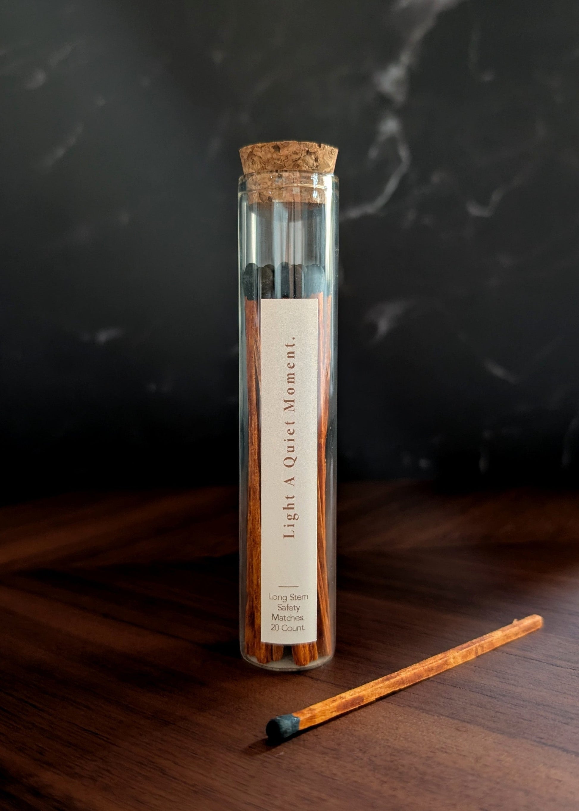 Espresso matches in a glass tube with cork top on a wooden table and dark background.