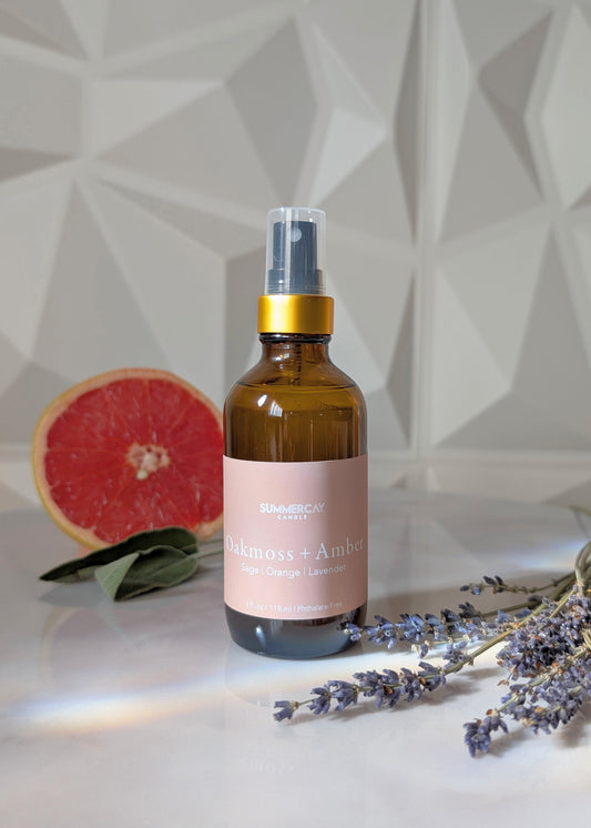 Room and linen spray with a pink label, lavender, and grapefruit on a geometric patterned background