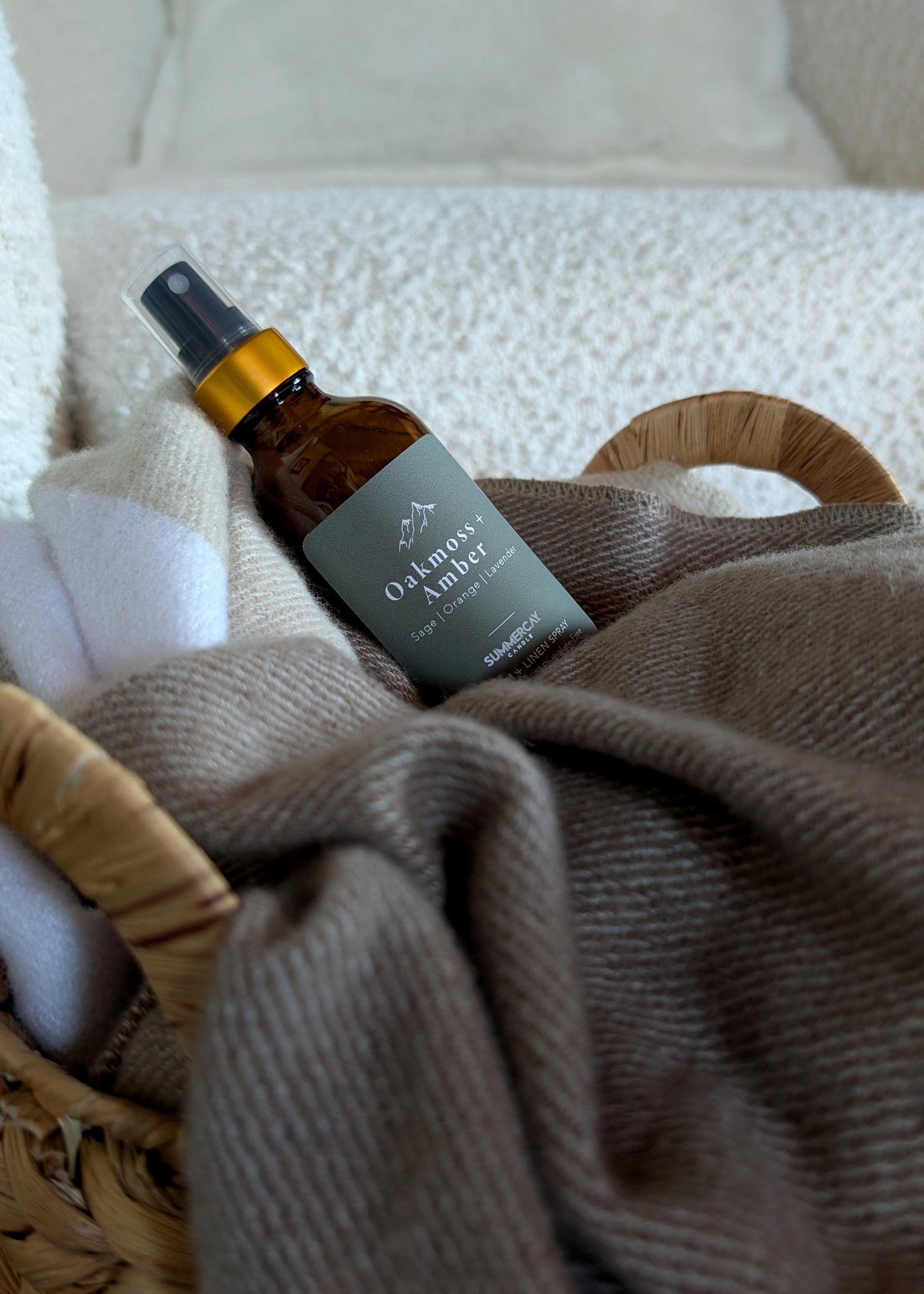 Room and linen spray in a woven basket with a soft blanket. 
