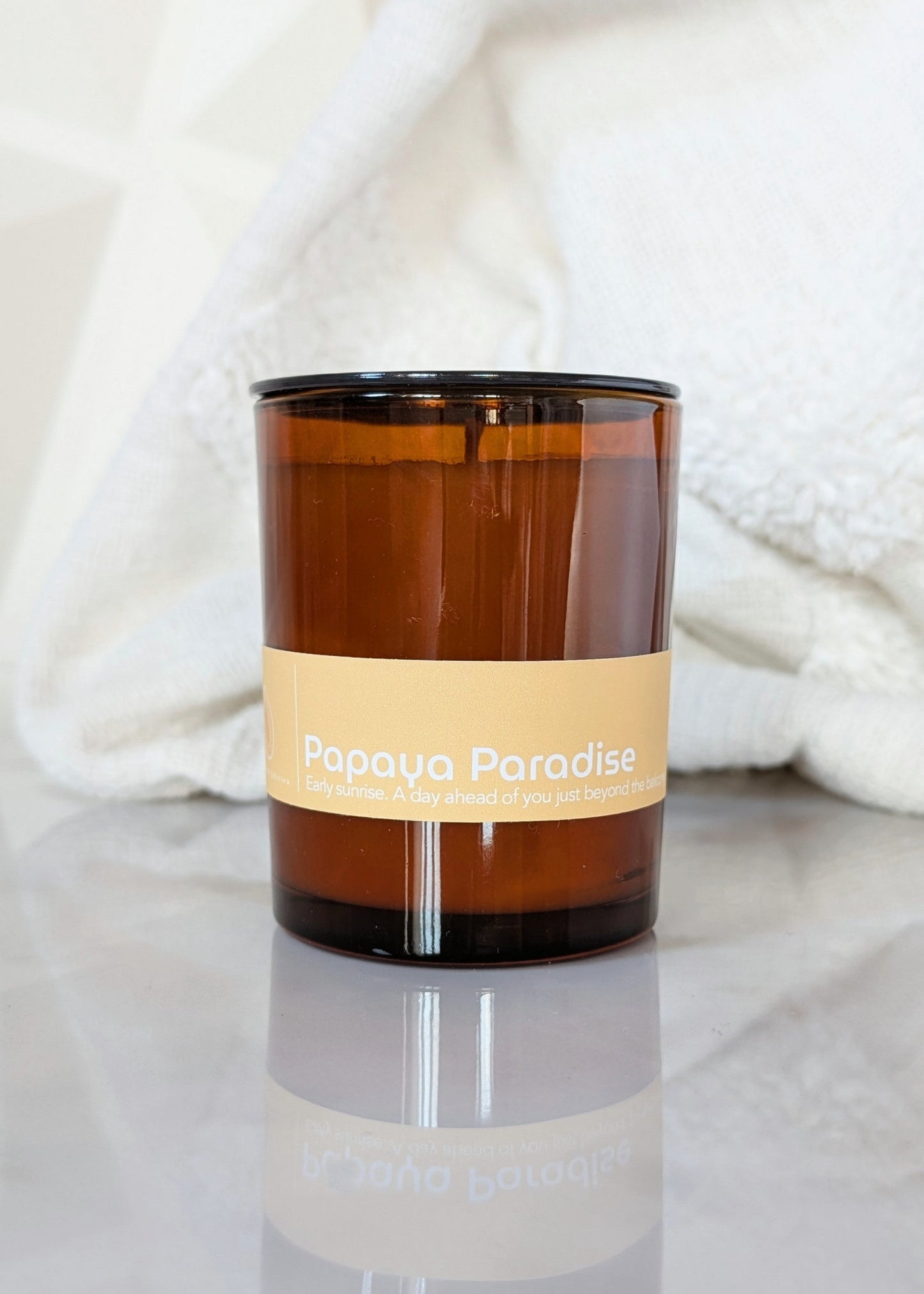 Amber glass Papaya Paradise candle on a light background.