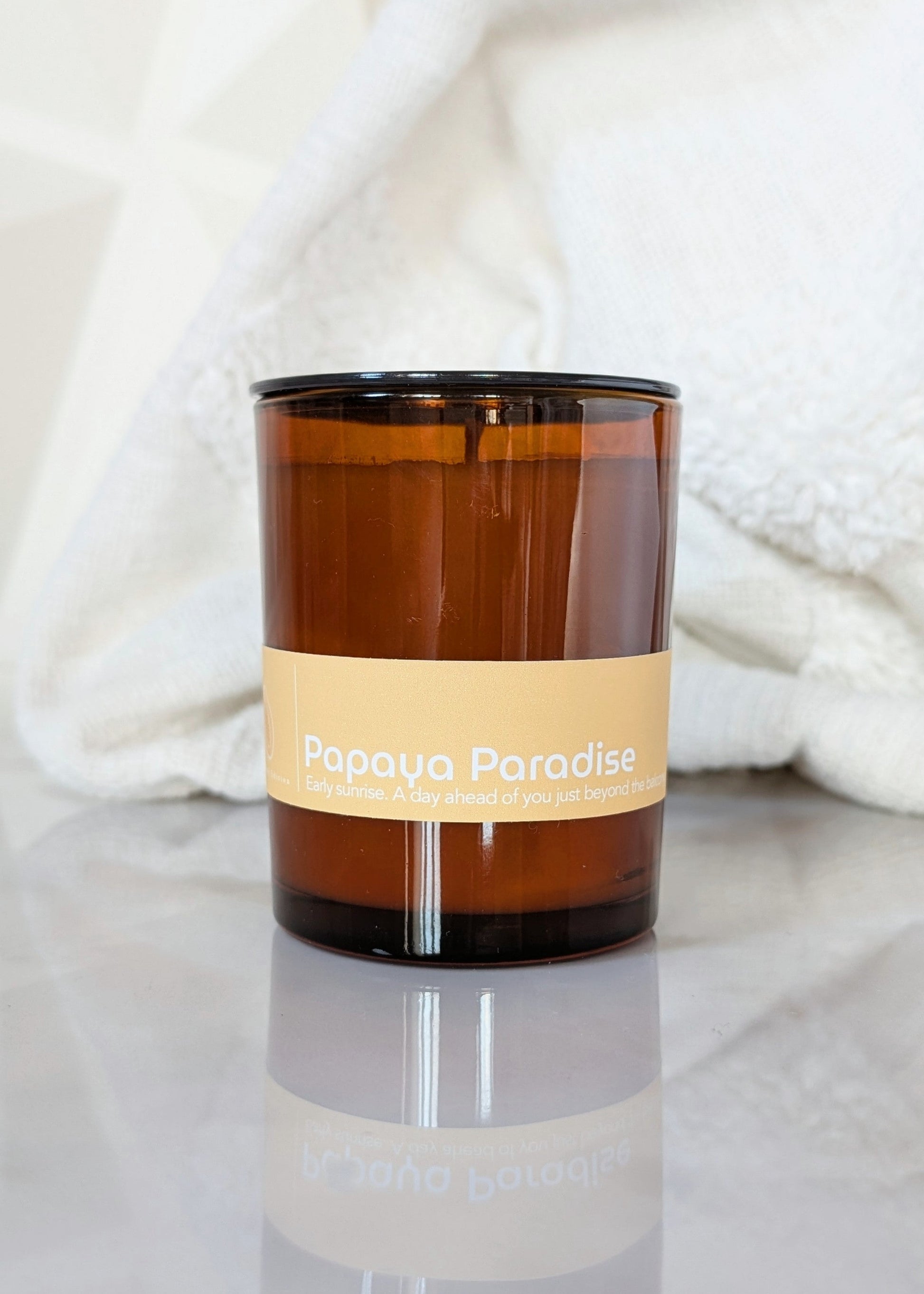 Amber glass Papaya Paradise candle on a light background.