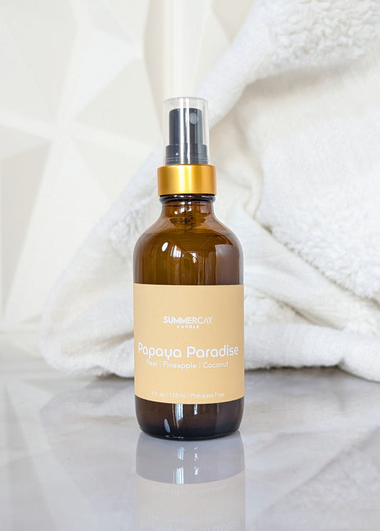 Papaya Paradise scented room spray in an amber glass spray bottle with gold and black top on a white background