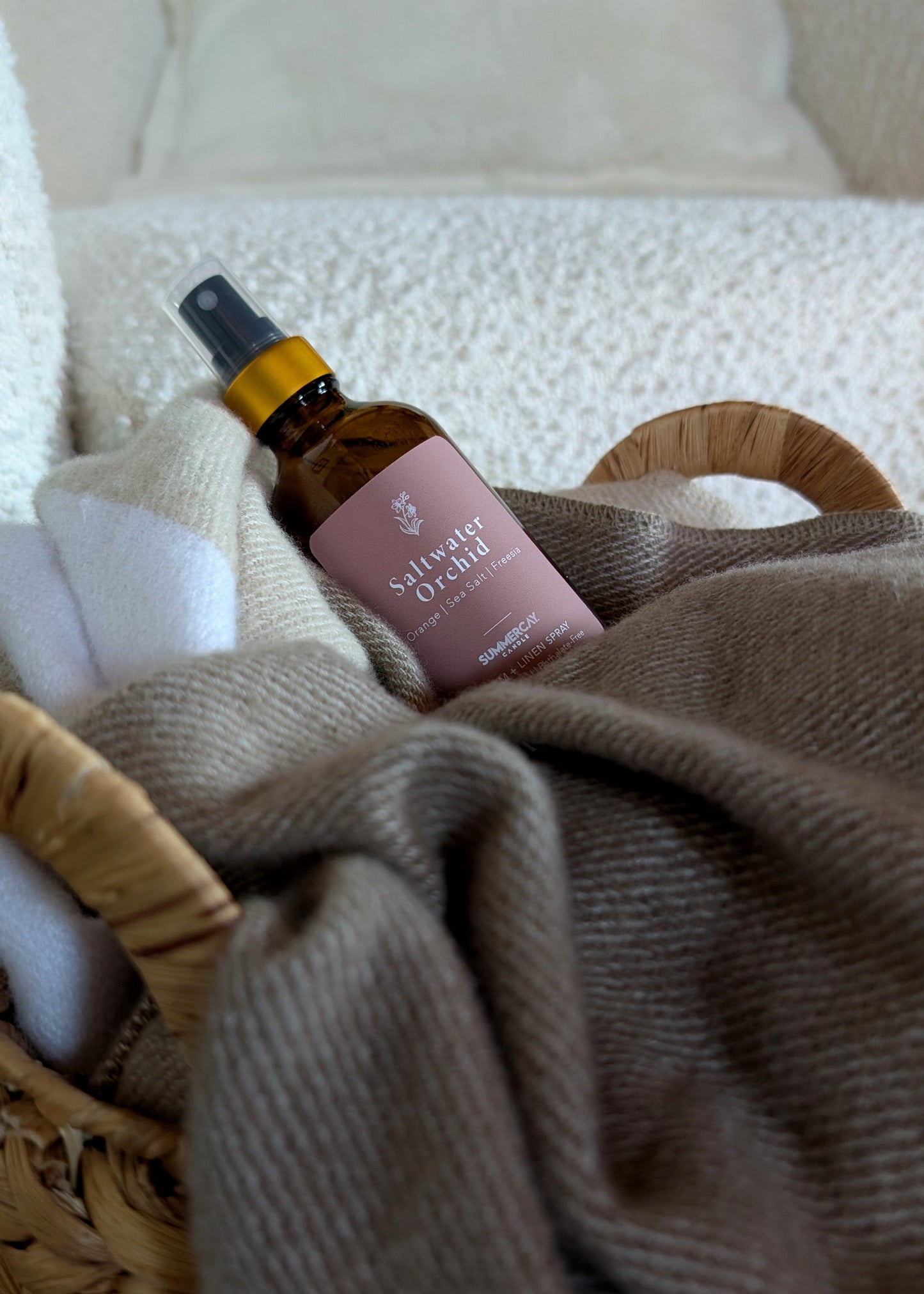 Saltwater Orchid room spray in a woven basket with a blanket