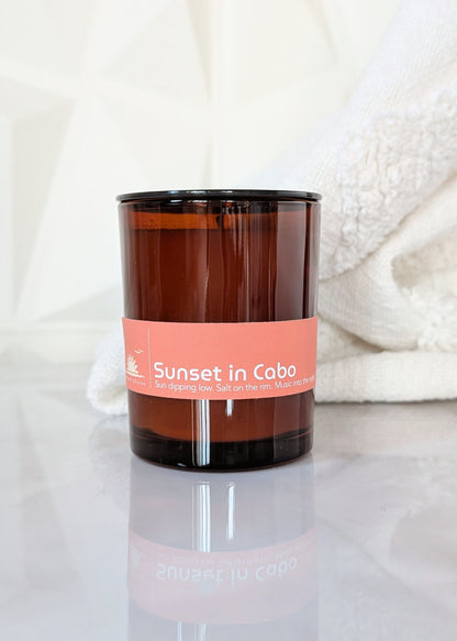Candle with a Sunset in Cabo label on a white surface