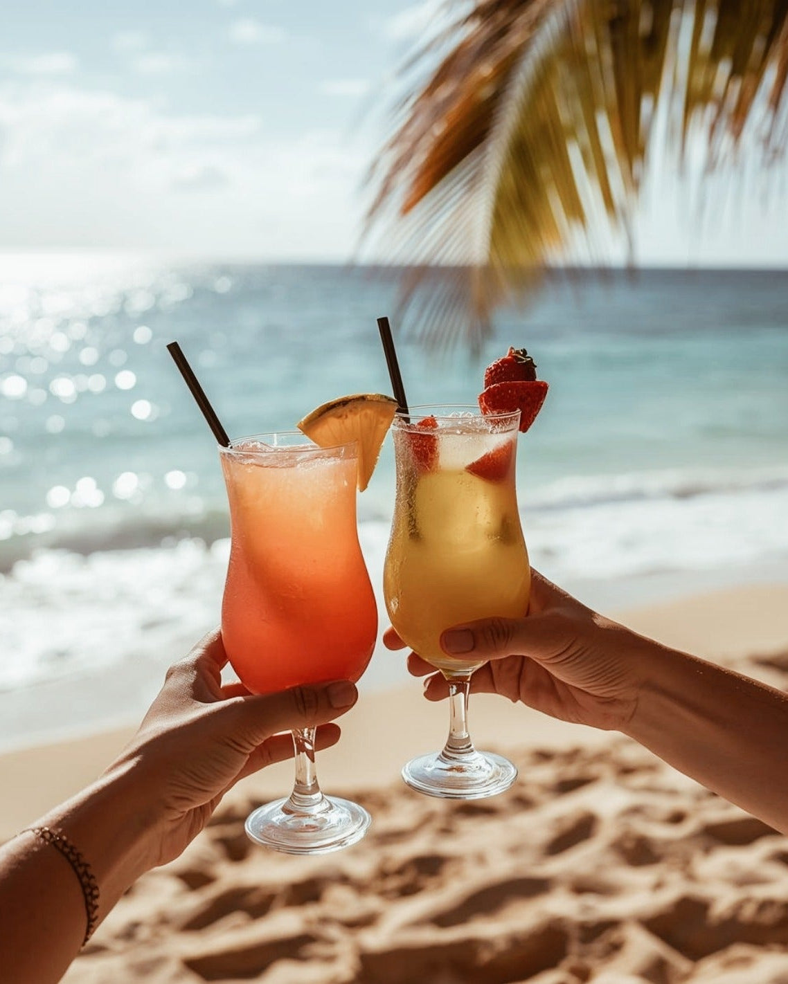 Two people holding cocktails on a beach with palm trees and ocean view