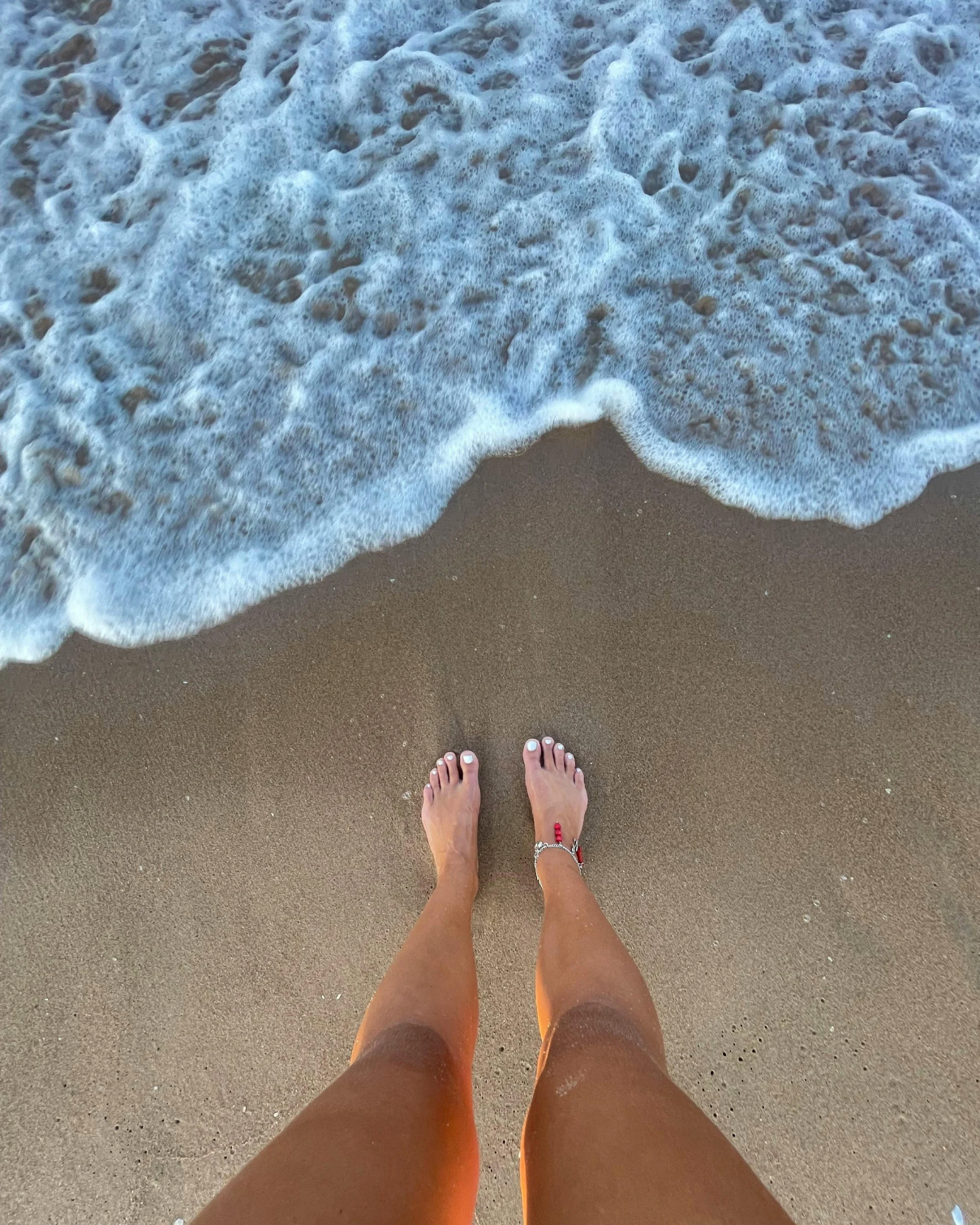 waves coming in and about to hit a woman's feet